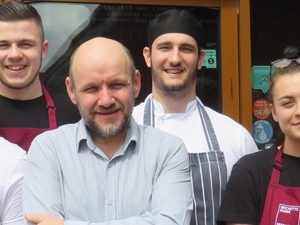 staff members pose for photo outside restaurant entrance to celebrate trip advisor certificate of excellence